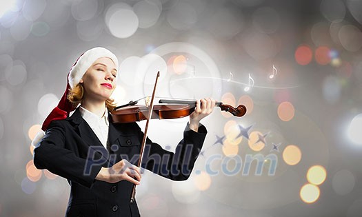 Woman in formal suit and Santa hat playing violin Woman in formal suit and Santa hat playing violin