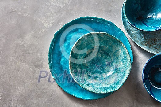Decorative pottery - bowls, plates covered with glazed on a gray background, place for text. Top view of traditional handcrafted. Decorative pottery - bowls, plates covered with glazed on a gray background, place for text. Top view of traditional handcrafted.