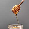 Sweet flower natural honey dripping into a jar and wooden spoon on a gray concrete background, copy space. Jewish rosh hashanah holiday concept.