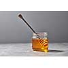 Sweet floral natural honey in a jar and wooden spoon on a gray marble table, copy space. Jewish rosh hashanah holiday concept.