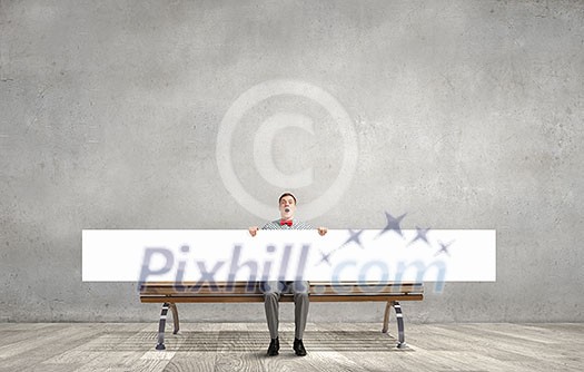 Young man with white blank banner sitting on bench Young man with white blank banner sitting on bench