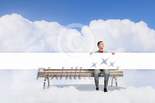Young man with white blank banner sitting on bench Young man with white blank banner sitting on bench