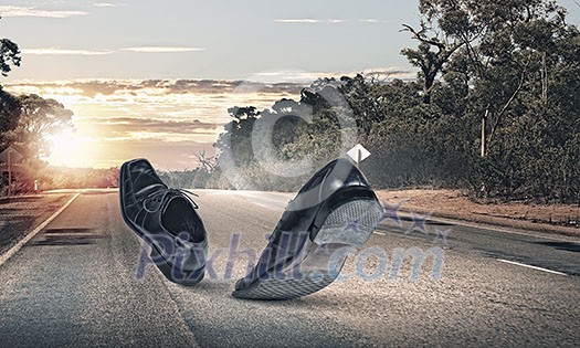 Pair of black shoes walking on road Pair of black shoes walking on road
