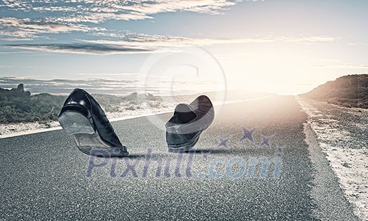 Pair of black shoes walking on road Pair of black shoes walking on road