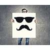 Businessman holding and hiding behind card with smiley face emoticon