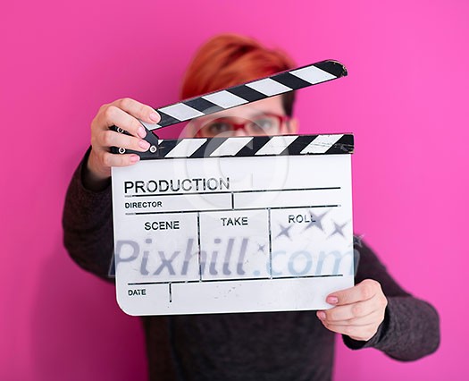 redhead woman holding movie clapper isolated against pink background cinema concept in studio redhead woman holding movie clapper isolated against pink background cinema concept in studio