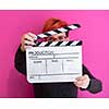 redhead woman holding movie clapper isolated against pink background  cinema concept in studio