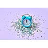 New Year alarm clock with almost twelve o'clock on a lavender background with holiday bright silver small stars tinsel, copy space.