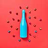 Decoration composition from blue painted bottle on a red background covered colorful glass New Year balls with copy space. Greeting holiday card