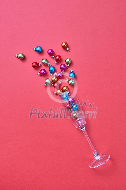 Christmas decoration balls in a glass as a champagne alcohol drink on a calypso coral background with plase for text. Greeting holiday card. Christmas decoration balls in a glass as a champagne alcohol drink on a calypso coral background with plase for text. Greeting holiday card.