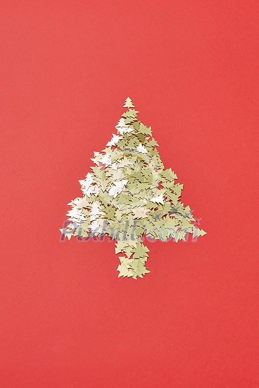 Creative Christmas decoration Tree from small shiny spruces on a red background with copy space. Greeting holiday card. Creative Christmas decoration Tree from small shiny spruces on a red background with copy space. Greeting holiday card.