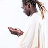 Handsome Young  African Muslim Man Making Traditional Fatiha Prayer To Allah God While Wearing A Traditional Sudan fashion clothes in studio