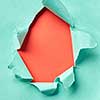 Handmade decoration frame from torn turquoise paper on a coral background with copy space. Can be used for your creativity.