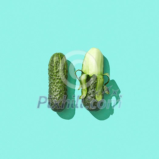 Peeled and whole cucumbers on a blue background with reflection of shadows and copy space for text. Healthy Diet Food. Top view Peeled and whole cucumbers on a blue background with reflection of shadows and copy space for text. Healthy Diet Food. Top view