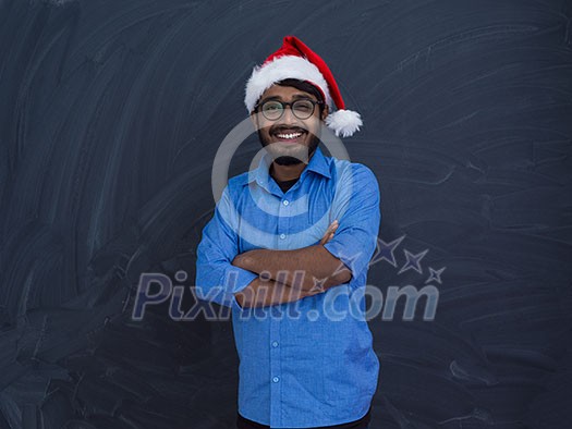 Indian man wearing traditional Santa Claus hat on chalkboard background studio dark-skinned Christmas santa new year party Indian man wearing traditional Santa Claus hat on chalkboard background studio dark-skinned Christmas santa new year party