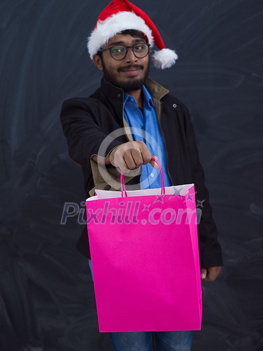 Indian man wearing party clothes in Santa hat with shopping bag on dark background studio dark skinned middle eastern Santa Claus merry Christmas Indian man wearing party clothes in Santa hat with shopping bag on dark background studio dark skinned middle eastern Santa Claus merry Christmas