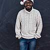 Indian man wearing traditional Santa Claus hat and white sweater  on chalkboard  background studio dark-skinned Christmas santa new year party