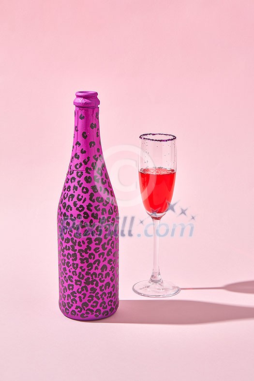 Glass of red wine with bottle painted hot pink with black spots and hard shadows on a pastel pink background, copy space. Glass of red wine with bottle painted hot pink with black spots and hard shadows on a pastel pink background, copy space.