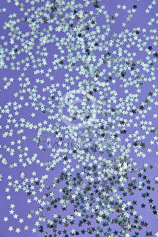New Year decoration from bright small stars confetti on a lilac background. Holiday creative layout. Top view. New Year decoration from bright small stars confetti on a lilac background. Holiday creative layout. Top view.