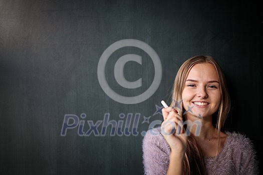 Pretty, young female student in front of a blackboard during class Pretty, young female student in front of a blackboard during class