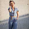 Pretty, young woman with headphones standing against concrete wall, enjoyig the hi-fi quality sound, listening to her favorite songs (color toned image)