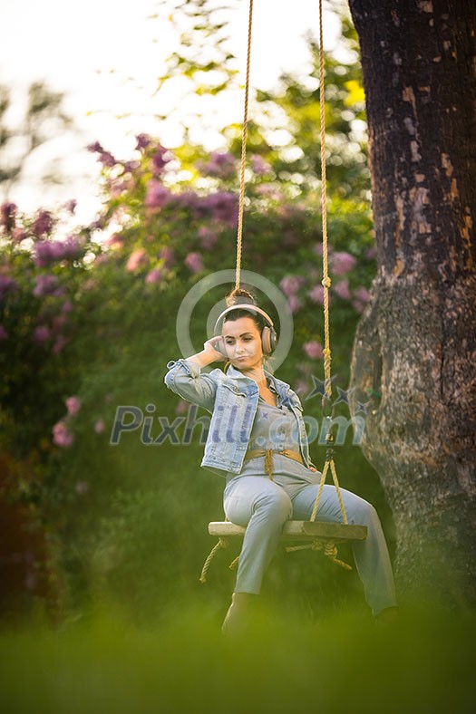 Pretty, young woman with headphones outdoors, in a lovely park, enjoyig the hi-fi quality sound, listening to her favorite songs (color toned image) Pretty, young woman with headphones outdoors, in a lovely park, enjoyig the hi-fi quality sound, listening to her favorite songs (color toned image)