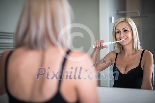 Pretty, middle aged woman brushing her teeth in a modern design bathroom Pretty, middle aged woman brushing her teeth in a modern design bathroom