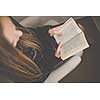Cute young woman reading a book in a designer chair - color toned image, shallow DOF