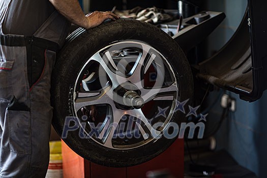 Wheel balancing or repair and change car tire at auto service garage or workshop by mechanic Wheel balancing or repair and change car tire at auto service garage or workshop by mechanic