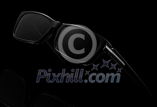 Modern black sun glasses on a dark background with copy space. Modern accessory for protection eyes. Modern black sun glasses on a dark background with copy space. Modern accessory for protection eyes.