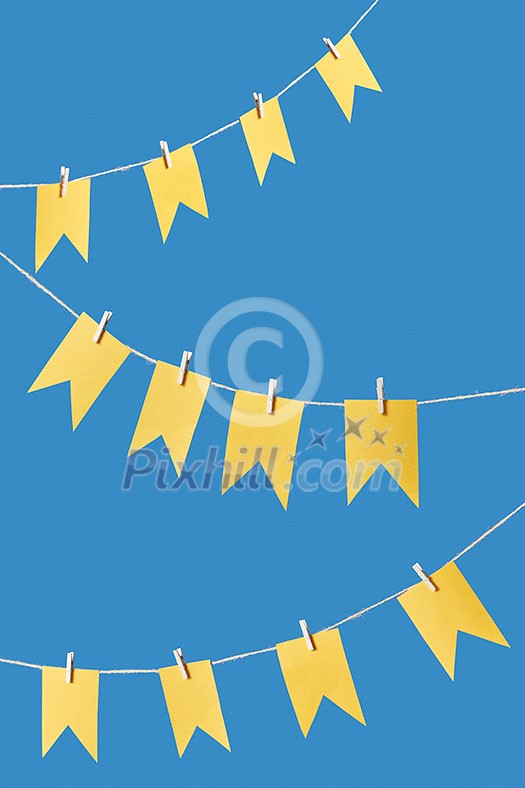 Holiday backdrop with hanging paper craft flags on a rope against blue background with copy space. Greeting card. Holiday backdrop with hanging paper craft flags on a rope against blue background with copy space. Greeting card.