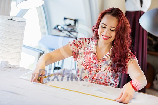Pretty dressmaker at work making patterns of fabric Pretty dressmaker at work making patterns of fabric