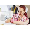 Young attractive woman dressmaker working with sewing machine