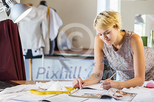 Pretty dressmaker at work making patterns of fabric Pretty dressmaker at work making patterns of fabric