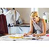 Pretty dressmaker at work making patterns of fabric