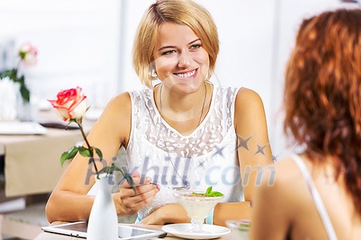 Two young pretty women sitting at cafe and eating dessert Two young pretty women sitting at cafe and eating dessert