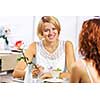 Two young pretty women sitting at cafe and eating dessert