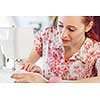 Young attractive woman dressmaker working with sewing machine