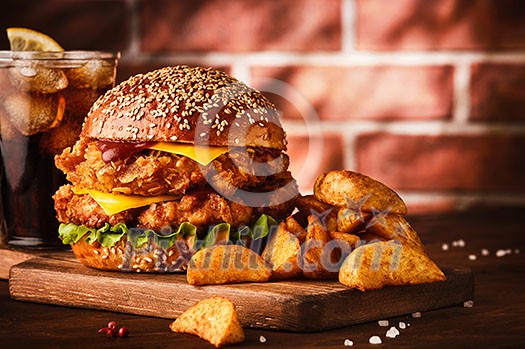 Fresh tasty homemade burger on wooden table. Big double cheddar cheeseburger with chicken cutlet with french fryes Fresh tasty homemade burger on wooden table. Big double cheddar cheeseburger with chicken cutlet with french fryes