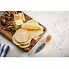 Different varieties of cheese with grapes and walnuts on a wooden board
