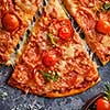 Slice of pepperoni pizza with cherry tomatoes. Sliced tasty pepperoni pizza on the grey stone background. Top view. Close-up.