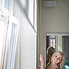 Pretty, young woman lowering the interior shades/blinds in her modern interior apartment