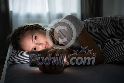 Pretty, young woman sleeping in her bed with her cell phone close to her. Smartphone in Bed Mobile/smartphone Addiction Concept. Pretty, young woman sleeping in her bed with her cell phone close to her. Smartphone in Bed Mobile/smartphone Addiction Concept.