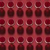 Geometric pattern from glasses with red wine alcoholic drink on a red background with hard shadows. Top view.