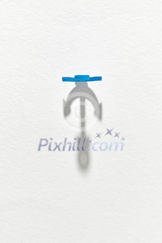 Big long shadows from blue plastic anchor on a light grey background with copy space. Top view. Big long shadows from blue plastic anchor on a light grey background with copy space. Top view.