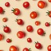 Freshly picked red ripe organic cherry tomatoes on a beige background. Top view. Vegetable vegan pattern.