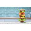 Video of homemade delicious burger with dancing fresh ingredients - two grilled beef cutlets, bacon, tomatoes and lettuce, cheese and sesame bun above a murble kitchen table. 4K UHD video 3840, 2160p.