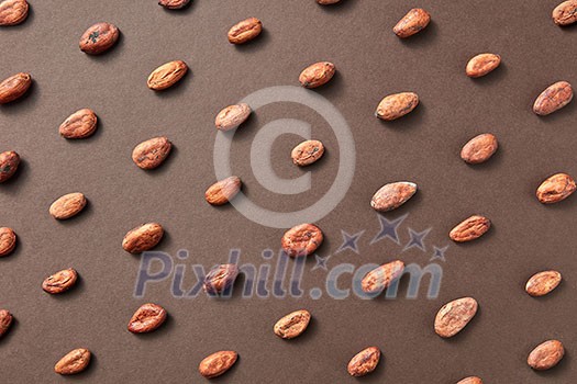 Natural fresh cacao beans on a brown background with soft shadows. Flat lay. Natural fresh cacao beans on a brown background with soft shadows. Flat lay.