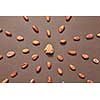 Part of fresh natural cocoa mass in the middle of food pattern from cacao beans on a brown background, copy space. Top view. Dry ingredients for making dark chocolate.