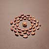Round frame from organic cocoa beans and cocoa mass in the middle on a brown background with soft shadows, copy space.